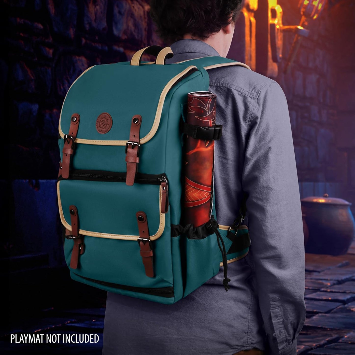 Teal backpack with tan trim worn by a person from behind, carrying a rolled mat. "PLAYMAT NOT INCLUDED" text. Stone passage.