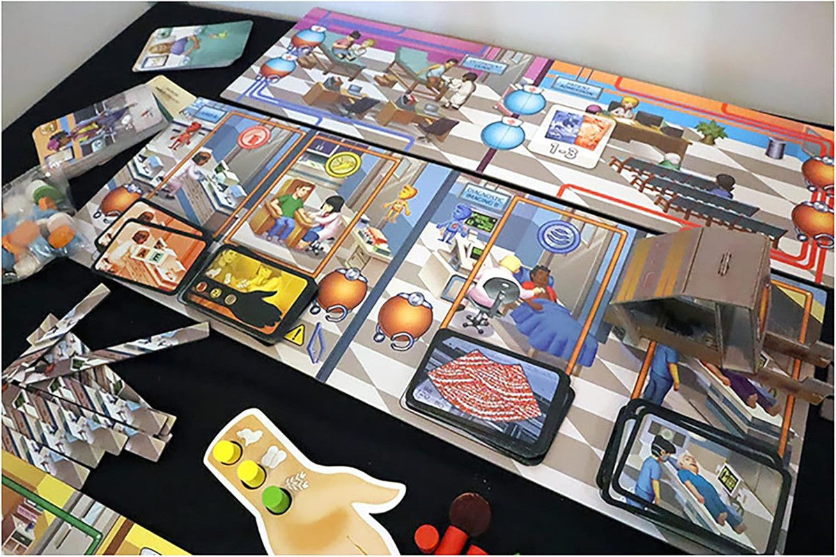 Overhead view of a hospital-themed board game setup, showing game board, patient cards, tokens, and cardboard pieces