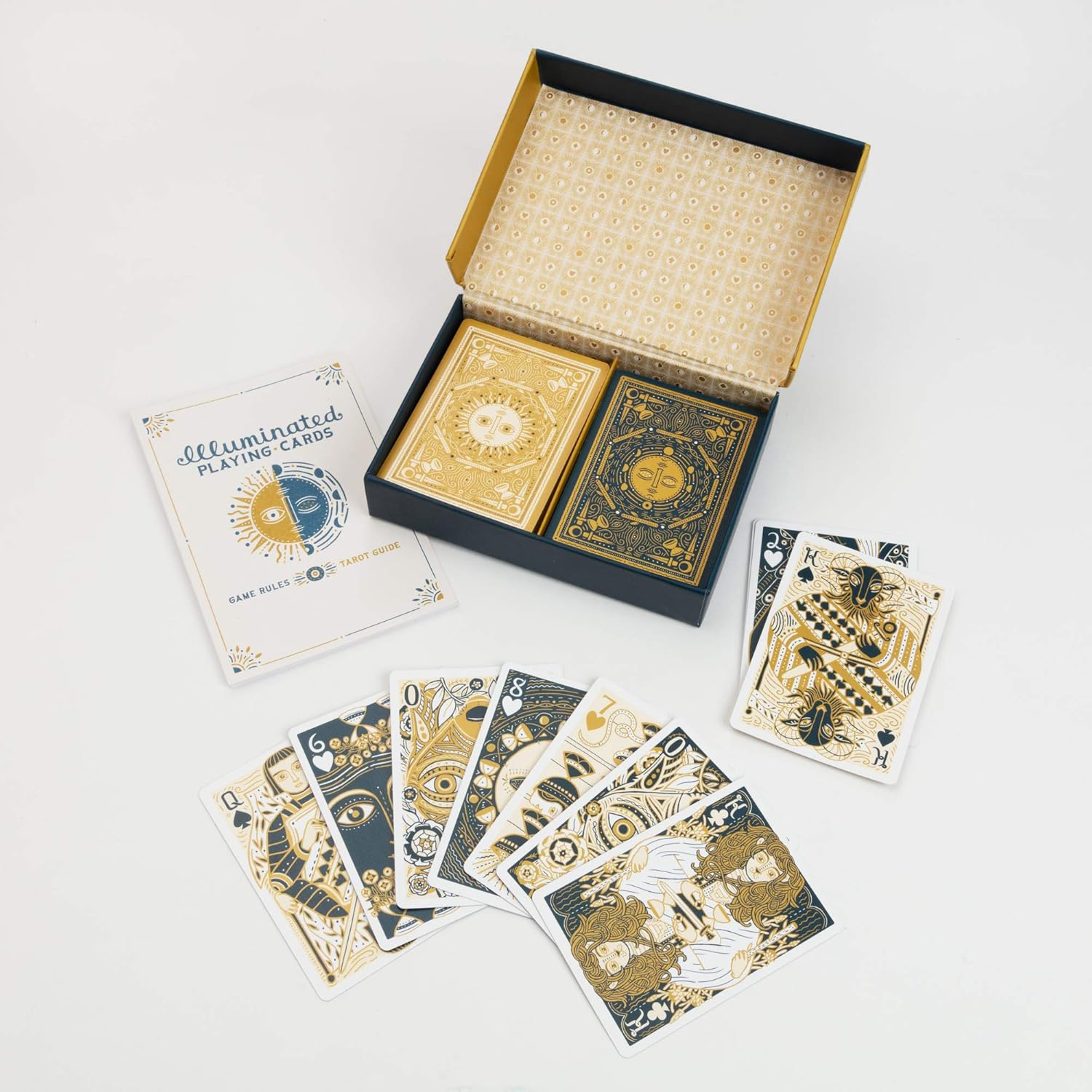 An open box of 'Illuminated Playing Cards' with two decks -  a rulebook -  and gold and blue designed cards fanned out
