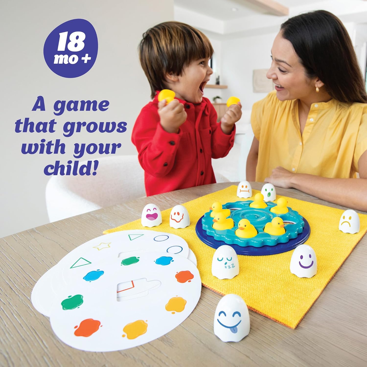 Excited boy and woman playing a game featuring rubber ducks, emotion tokens, and color cards
