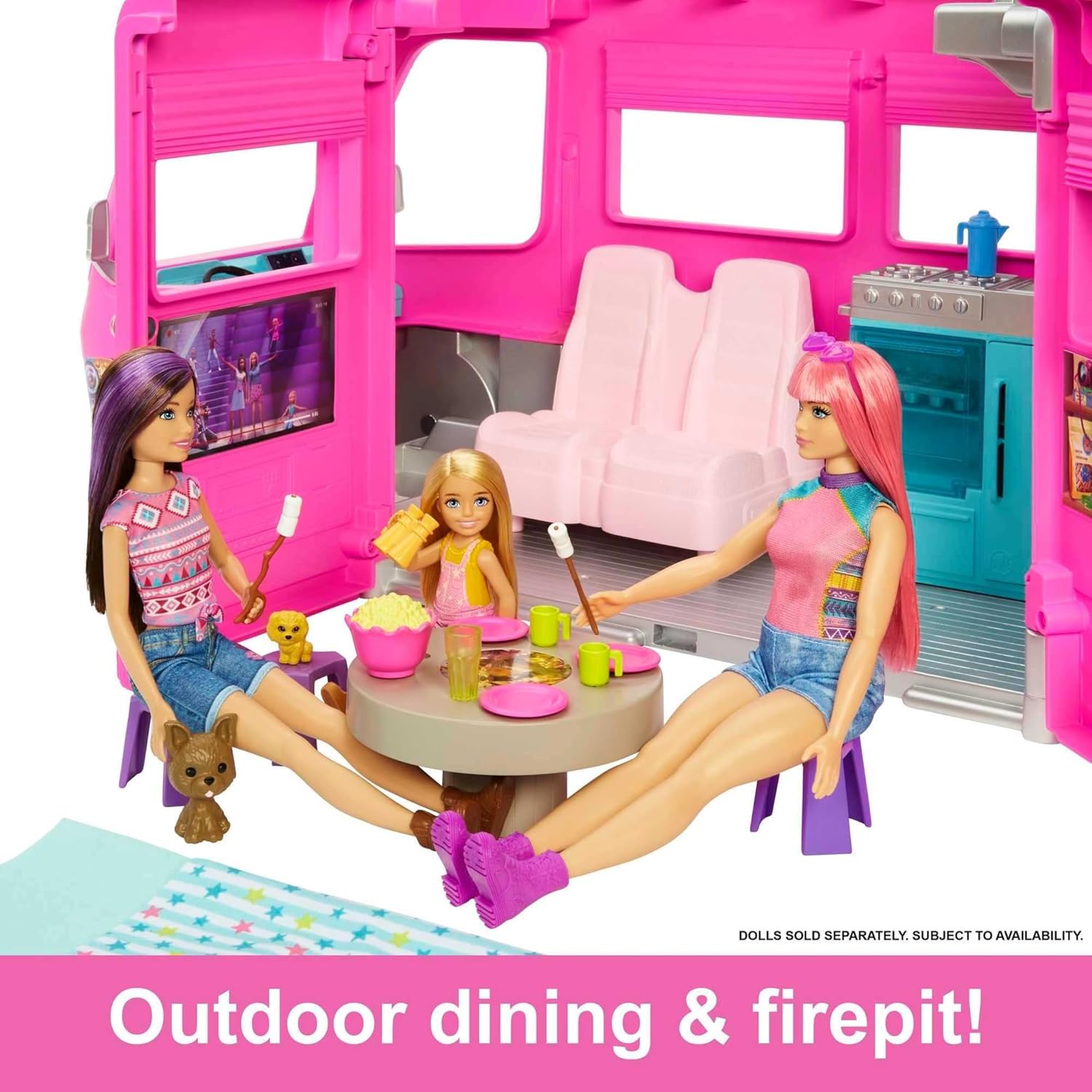 Three Barbie dolls and two dogs enjoy outdoor dining and marshmallow roasting next to a pink camper