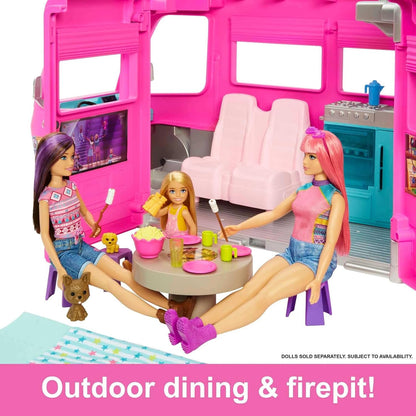 Three Barbie dolls and two dogs enjoy outdoor dining and marshmallow roasting next to a pink camper
