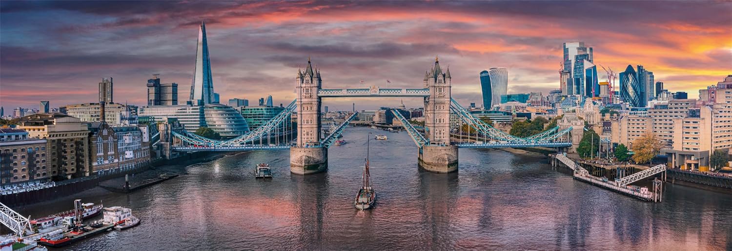 London's Tower Bridge raised over the Thames as a sailboat passes below, framed by the city skyline and sunset
