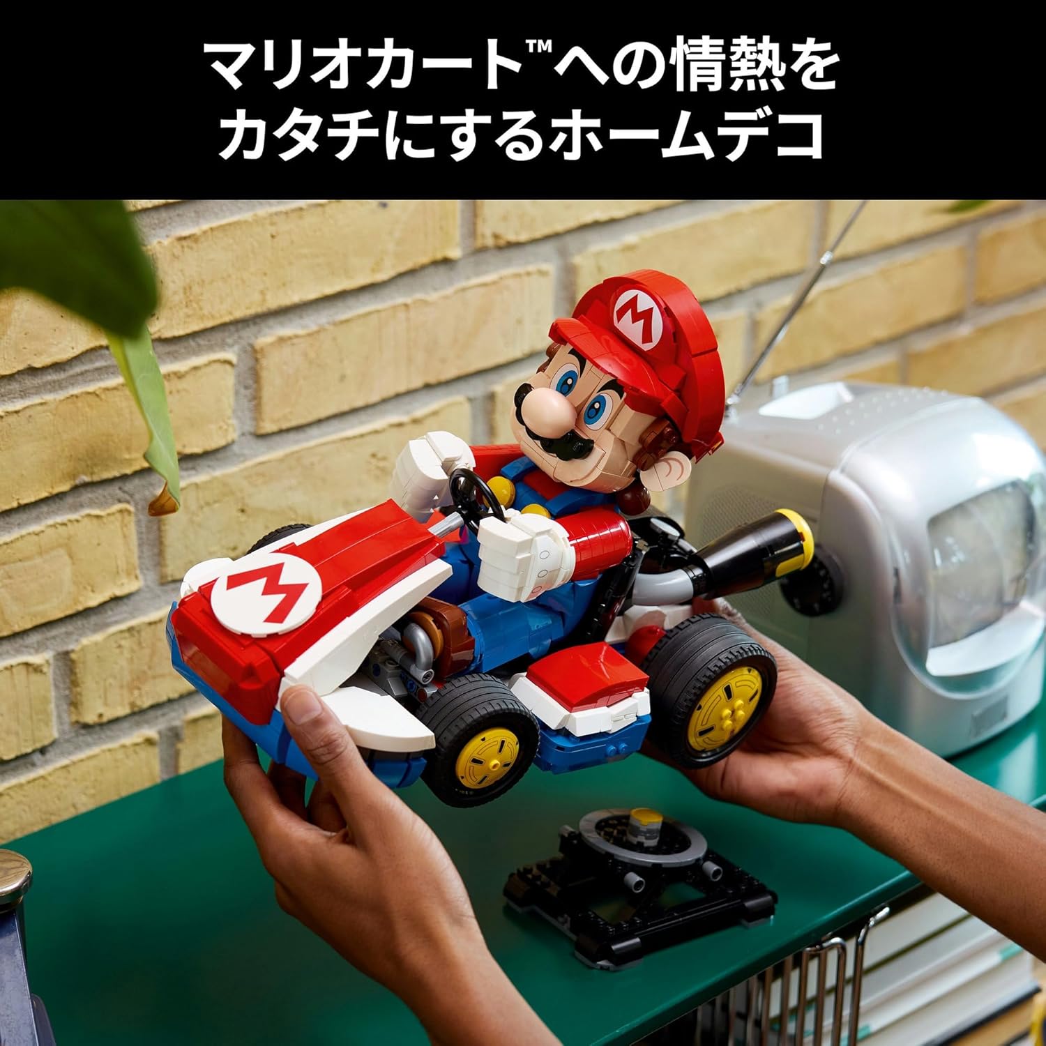 Hands displaying a detailed brick-built model of Mario in his red racing kart