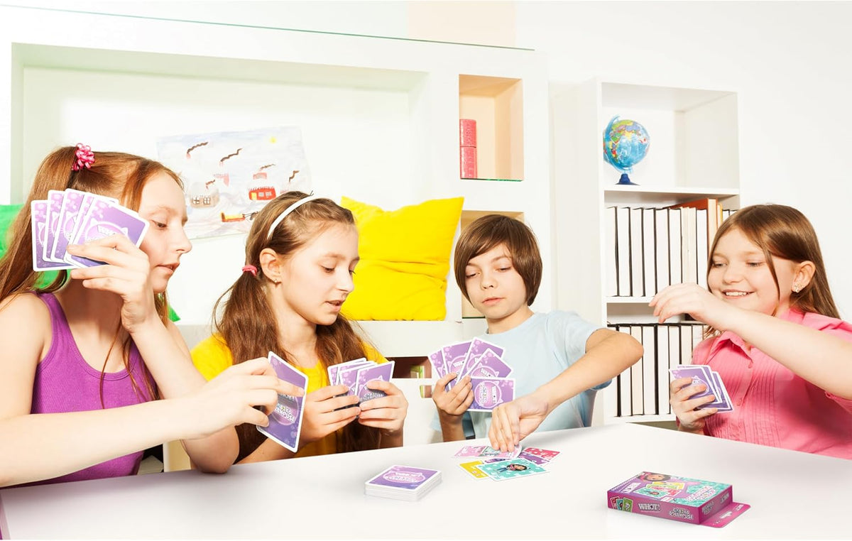 Four children play a card game with purple cards, called &quot;Crazy Dollhouse&quot;, at a white table