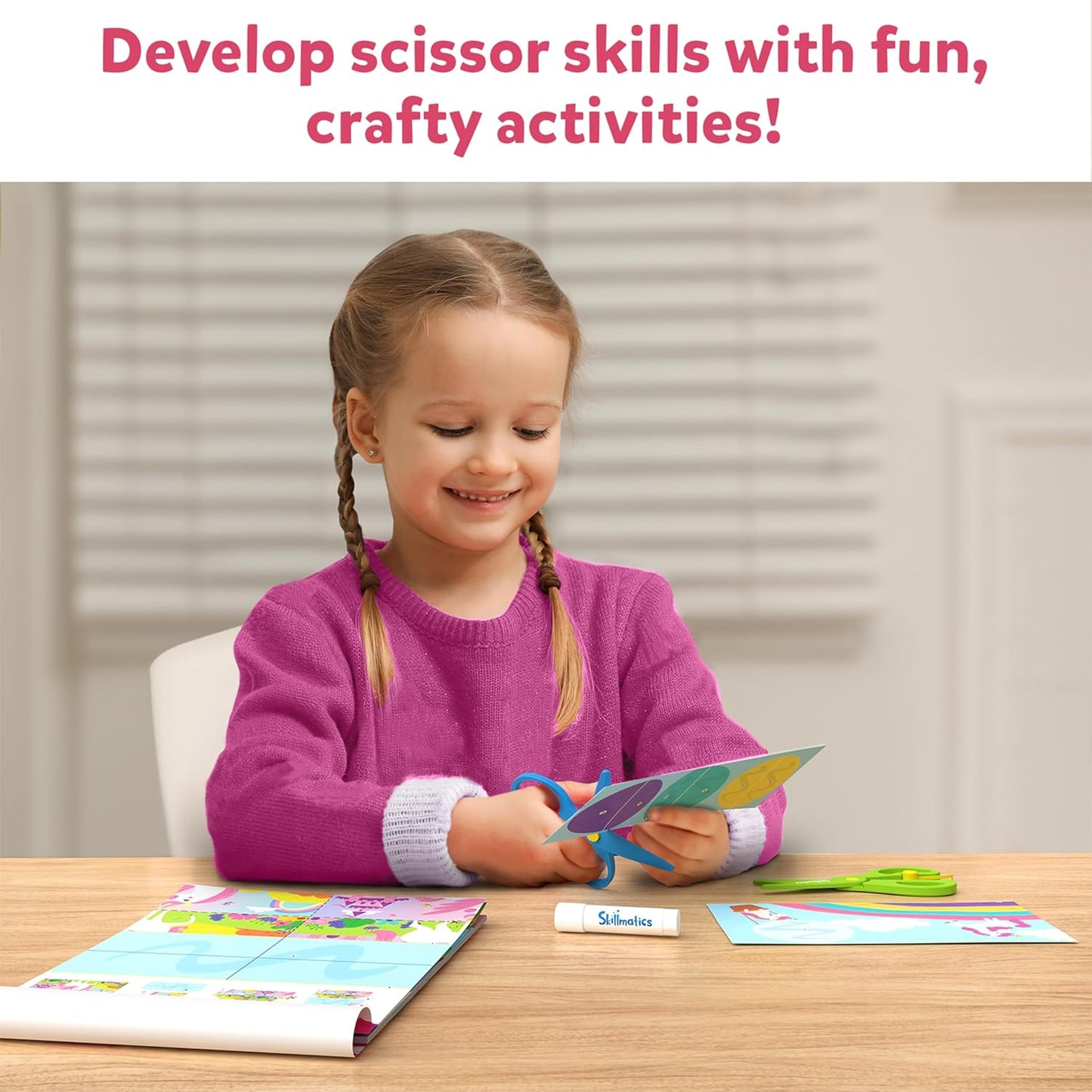 Happy girl practicing scissor skills, cutting colorful paper with blue safety scissors