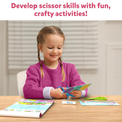 Happy girl practicing scissor skills, cutting colorful paper with blue safety scissors
