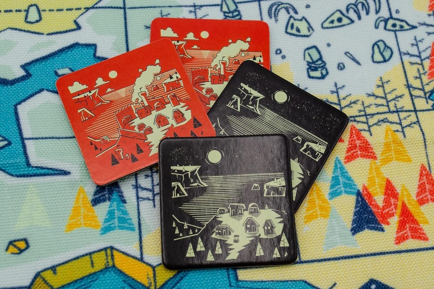 Four overlapping square game tiles show red day and black night village scenes on a colourful mat.