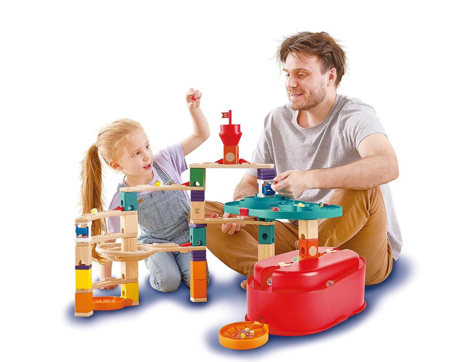 Smiling father and daughter playing together with a large, colorful wooden marble run toy
