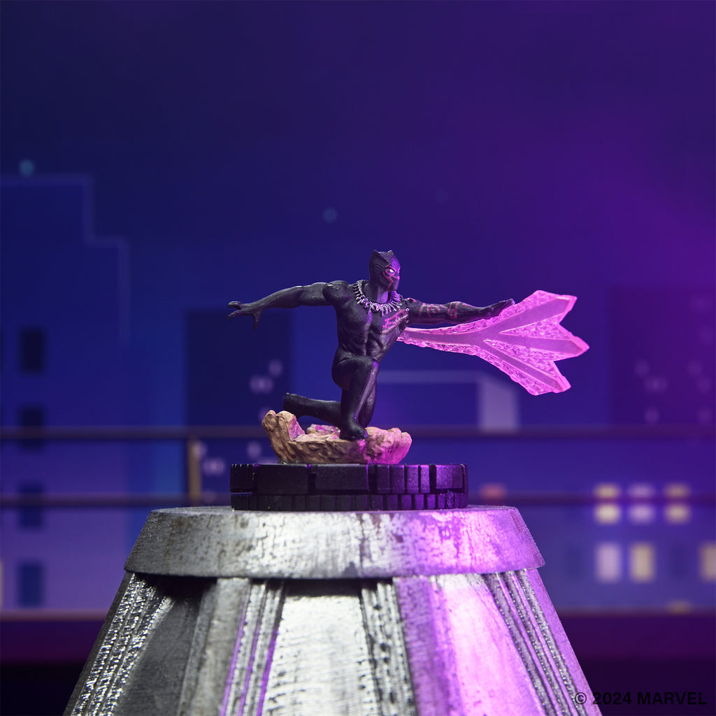 Black Panther miniature in a dynamic, leaping pose, emitting glowing purple energy effects. Blurred city lights in background