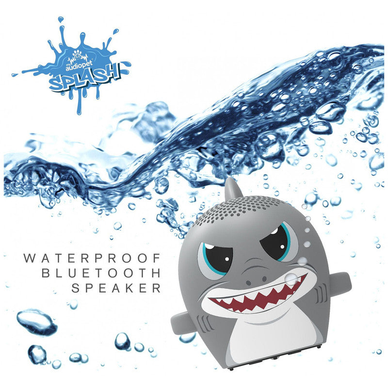Gray shark-shaped portable waterproof Bluetooth speaker with large grin and blue eyes splashing water in background