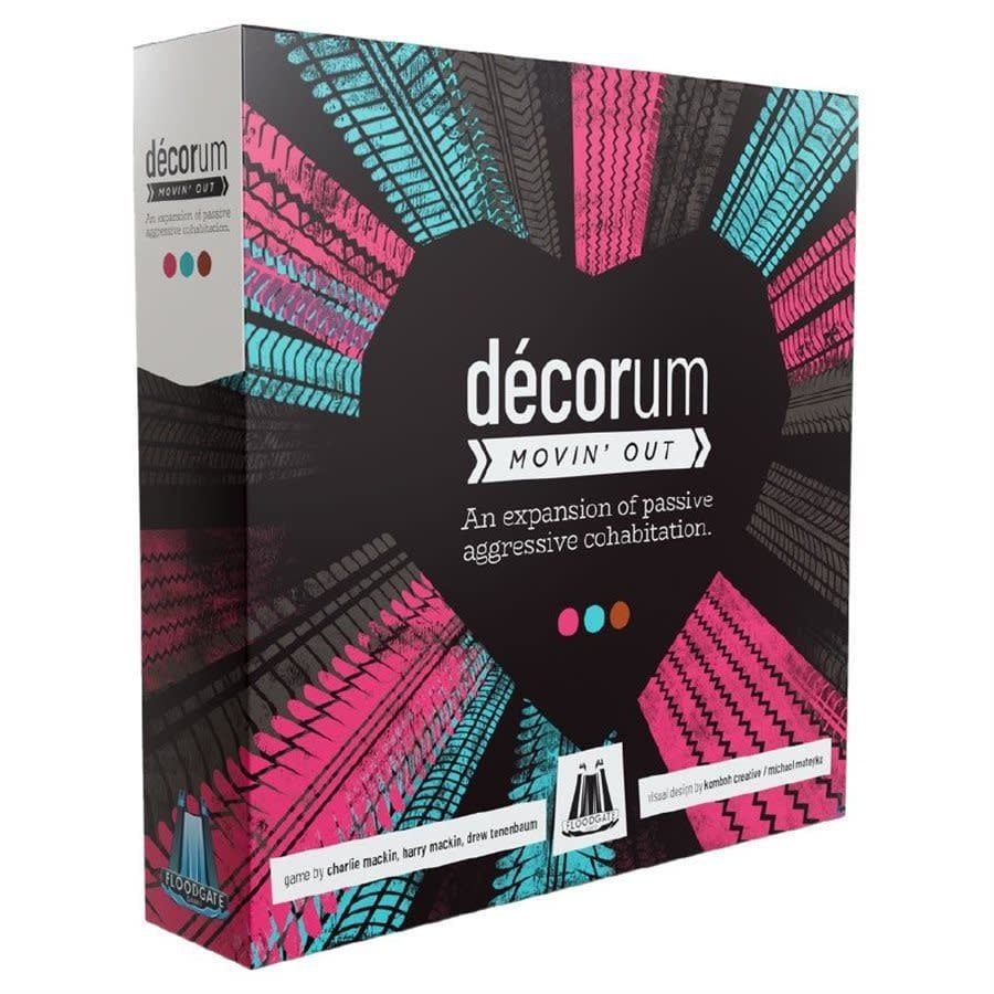 Décorum Movin' Out Expansion board game box with a heart-shaped design and radiating pink, turquoise, and grey tire tracks on a black background