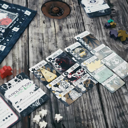 Horror-themed board game cards featuring titles like Cannibal Cave and Bone Pits are displayed alongside white and colored wooden player tokens