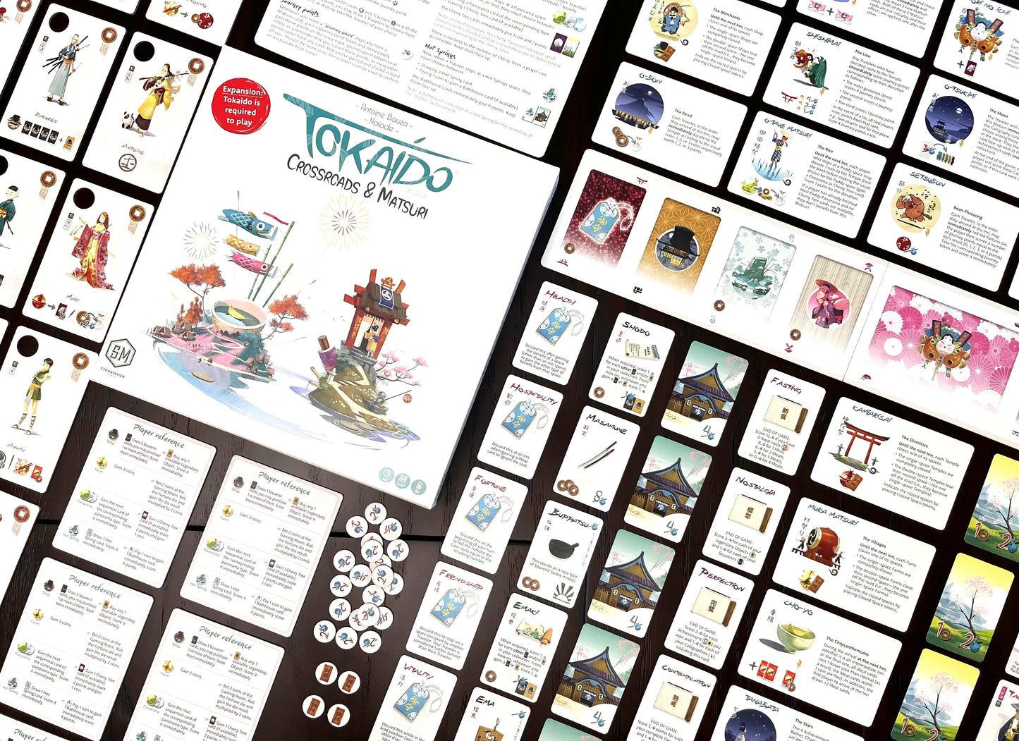 The Tokaido Crossroads and Matsuri board game expansion is displayed with its illustrated box art, player reference cards, and many colorful event tokens laid out