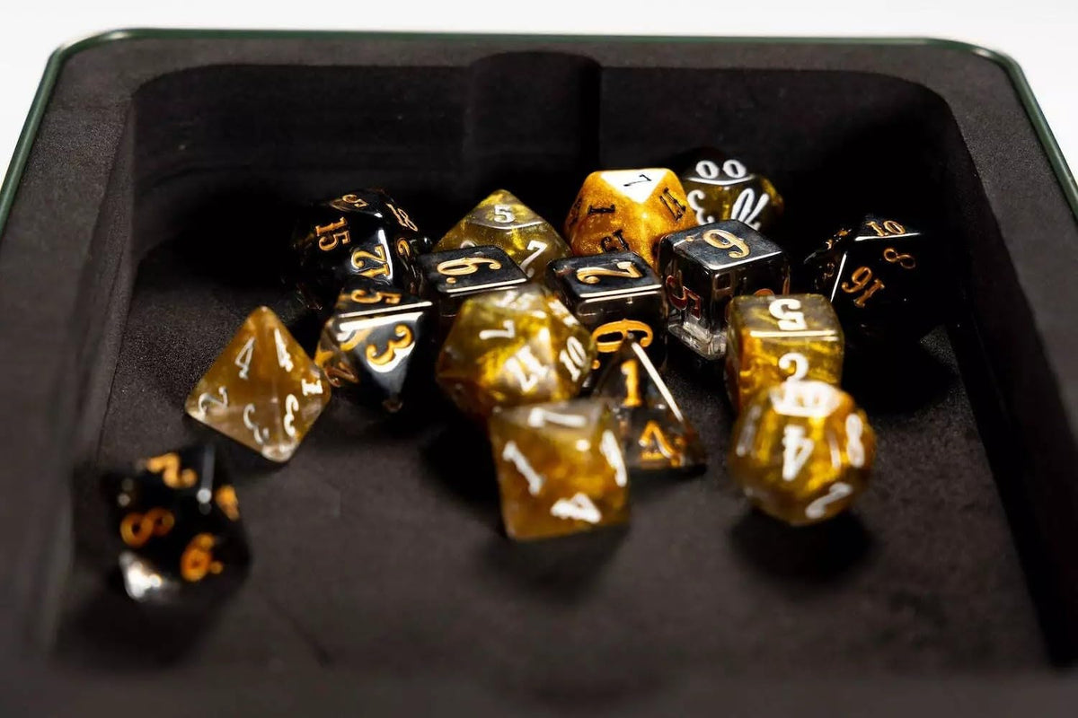 Black and gold polyhedral dice are scattered inside a dark, felt-lined rolling tray