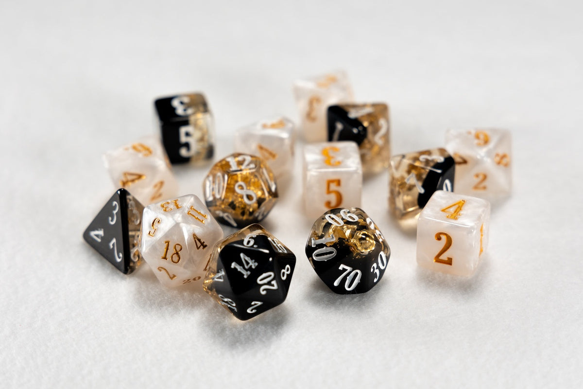 A scattered collection of black, white, and gold Beadle and Grimm&#39;s Cleric dice, some translucent with gold flakes