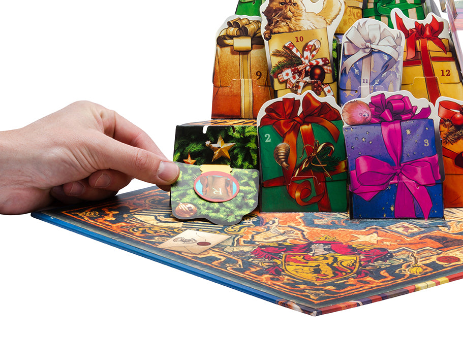 A hand pulls open a Christmas-themed advent calendar door, revealing an 'R' on its inner flap