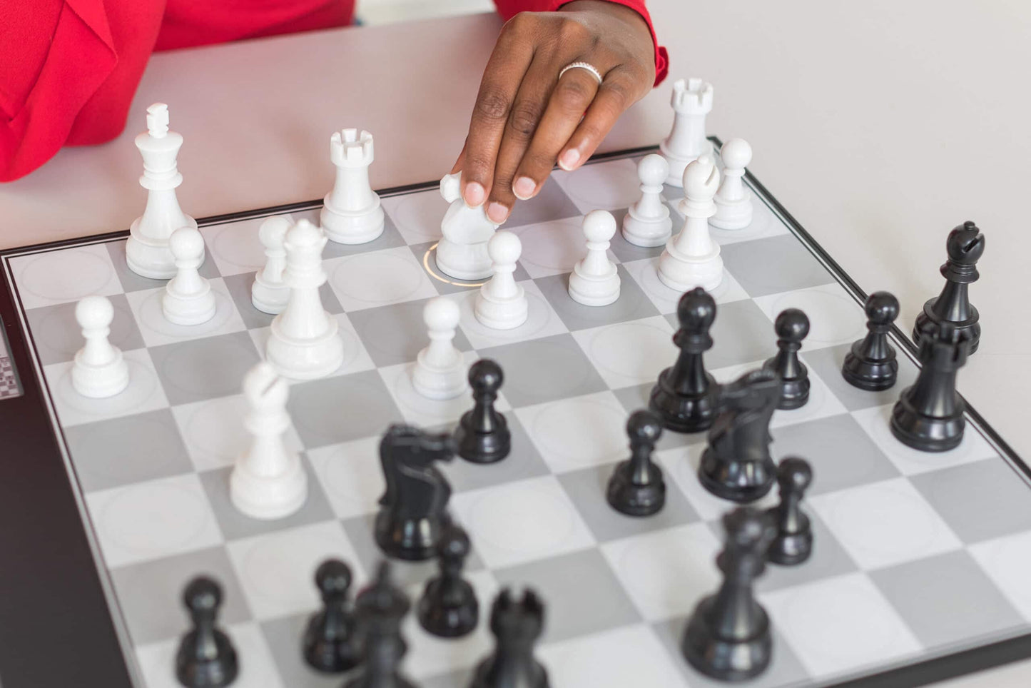 A DGT Centaur Chess Computer board with gray and white squares and a black border while a player's hand moves a white knight piece