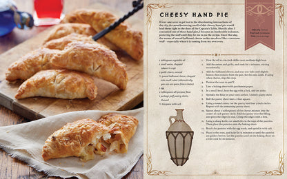 An open cookbook page shows the 'Cheesy Hand Pie' recipe on the right, with golden-brown hand pies, one broken open, on a wooden board to the left