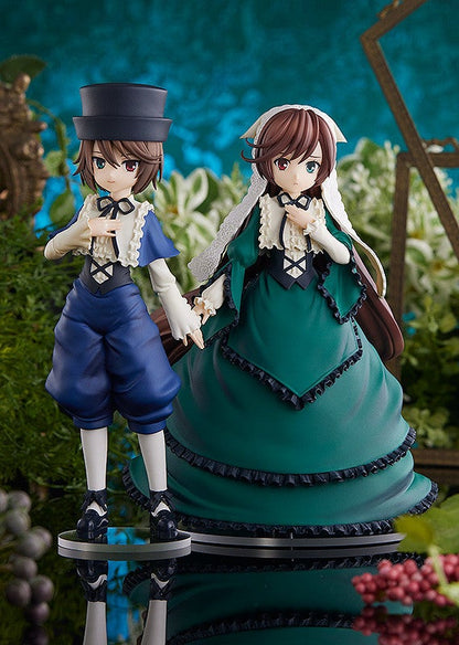 Two anime style figures a boy in a black top hat and blue outfit and a girl in a deep green dress with a white lace cap stand together