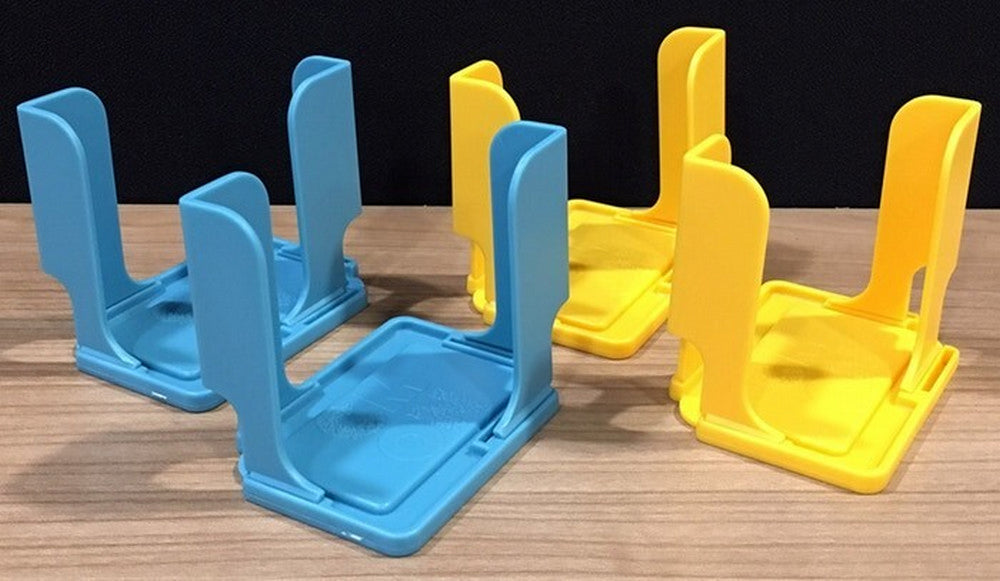 Two blue and two yellow plastic stands, likely for cards, are arranged on a wooden table