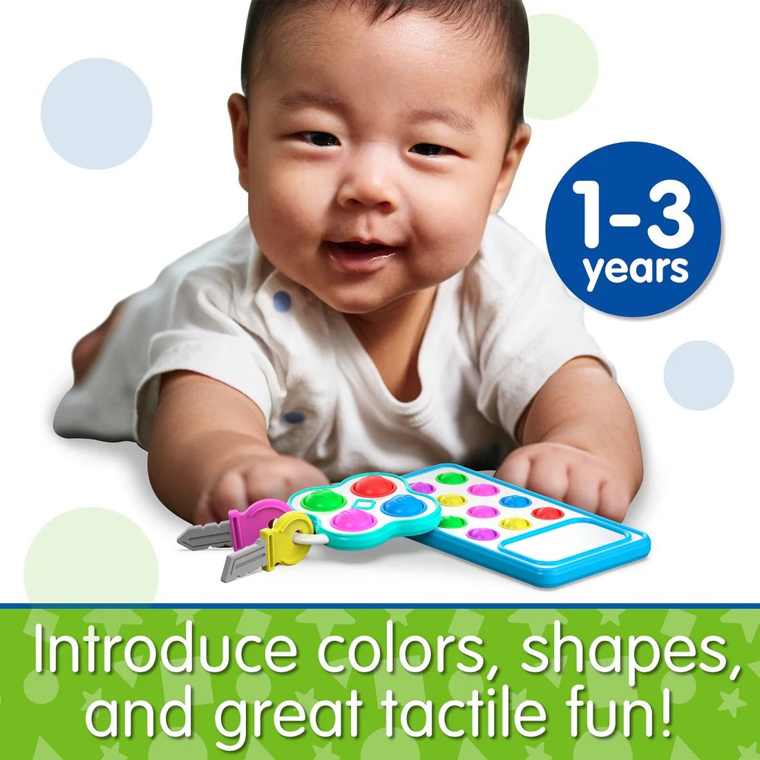 Smiling infant reaching for a colourful toy remote control and attached plastic keys