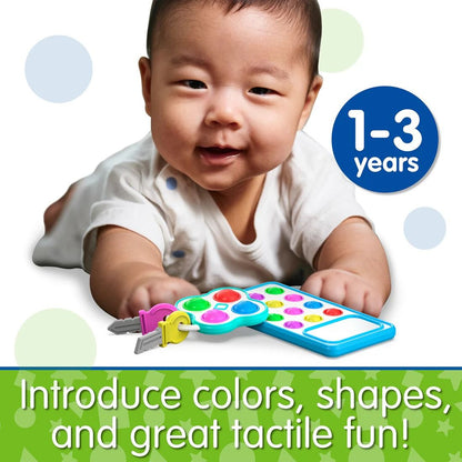 Smiling infant reaching for a colourful toy remote control and attached plastic keys
