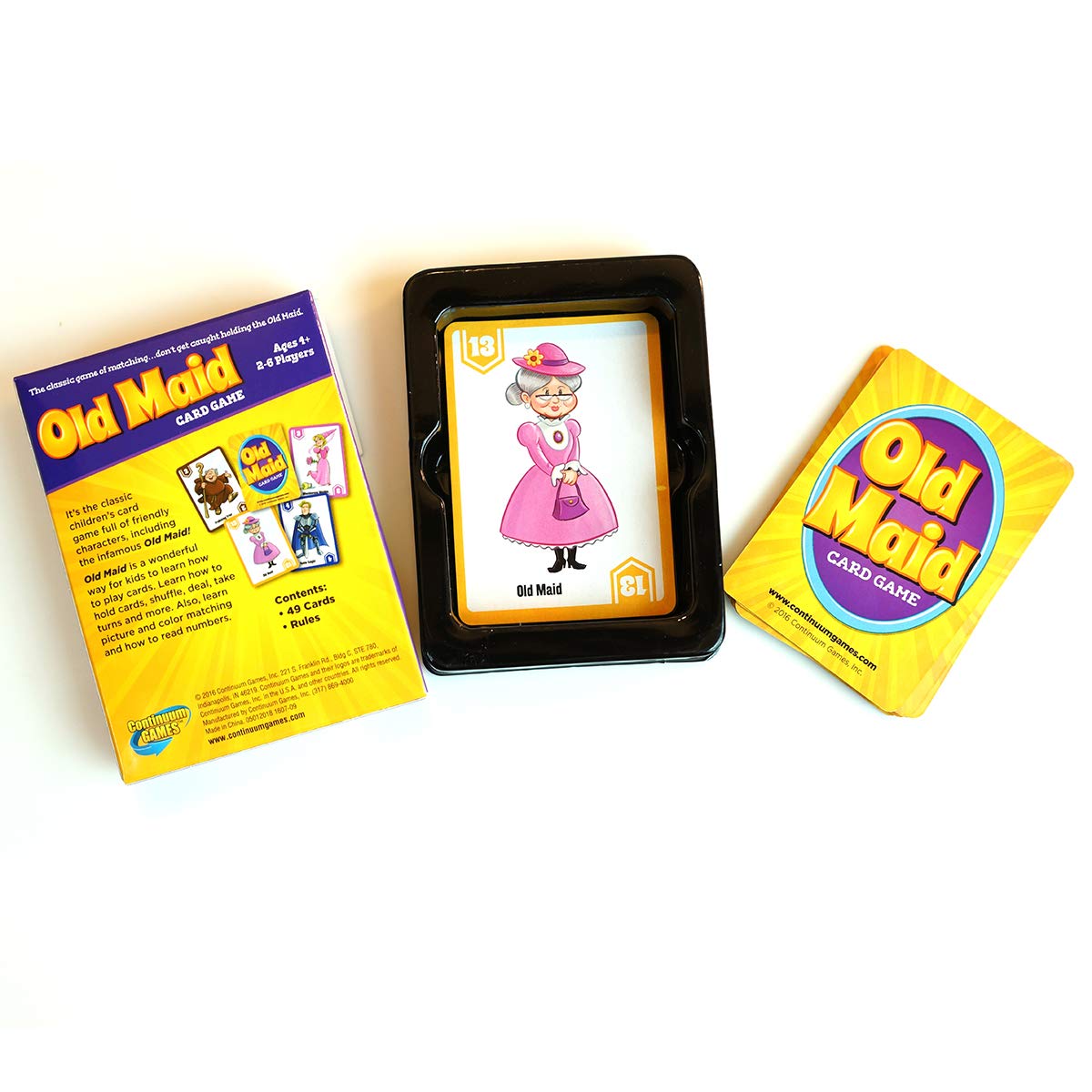 Continuum Games Old Maid Card Game components are spread out featuring the yellow packaging the specific Old Maid character card in a tray and a stack of yellow backed cards