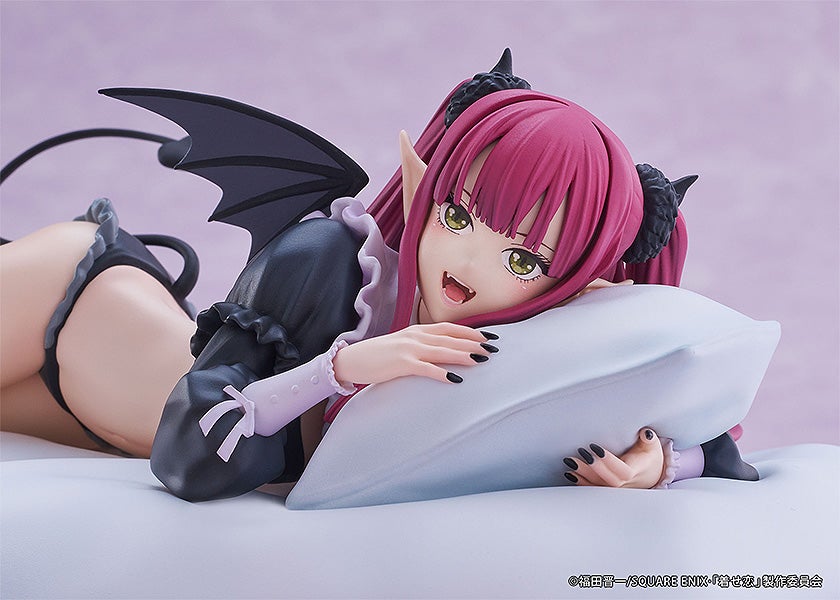 Pink-haired anime figure in devil outfit lying on stomach on a pillow