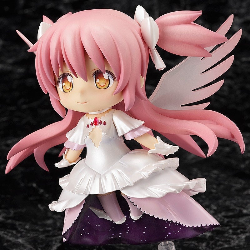 A smiling chibi anime figure with pink pigtails, white wings, a white ruffled dress, and golden eyes