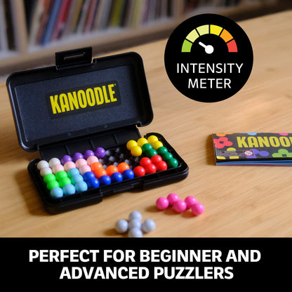 Open Kanoodle puzzle case showing colourful, interlocking spherical pieces and the instructions booklet on a wooden table
