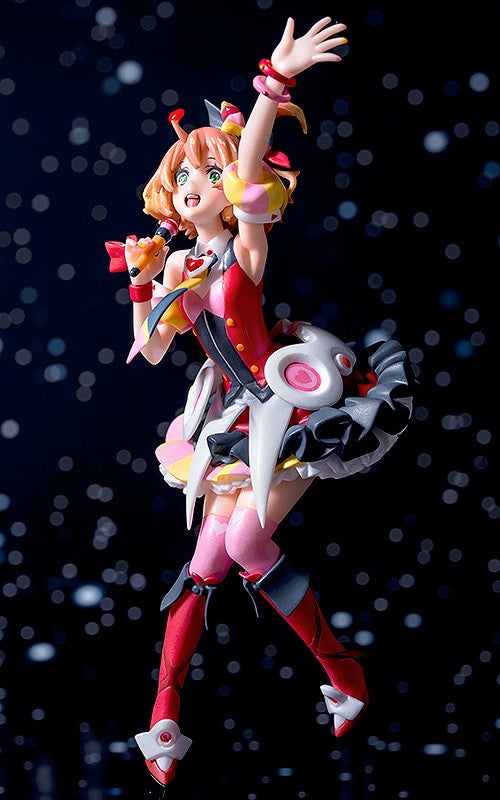 Anime idol figure in red and pink singing into a microphone with arms raised standing