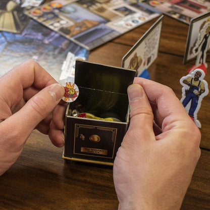 Hands placing a bomb token on a "The Mansky Safe Co." safe in a board game