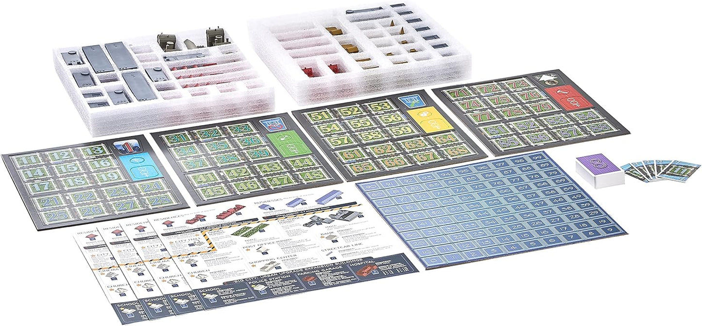 Board game components laid out: numbered grid boards, foam trays with tiny buildings and tokens, and various cards.