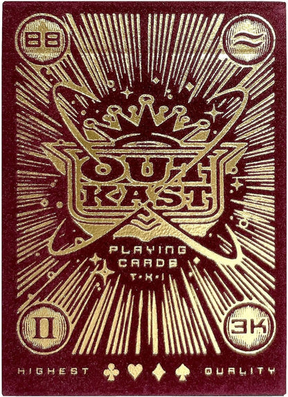 Maroon playing card back with intricate gold foil design featuring a stylized crown, radiating lines and the text 'OUTKAST