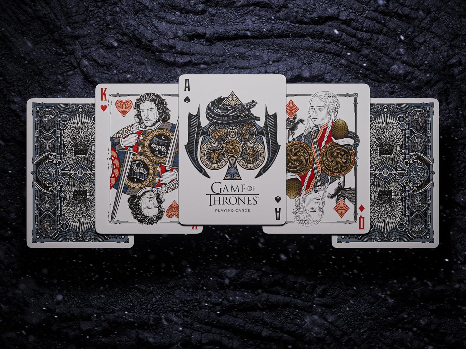 Game of Thrones playing cards displayed face-up (King, Queen and branded Ace) on a dark, textured surface