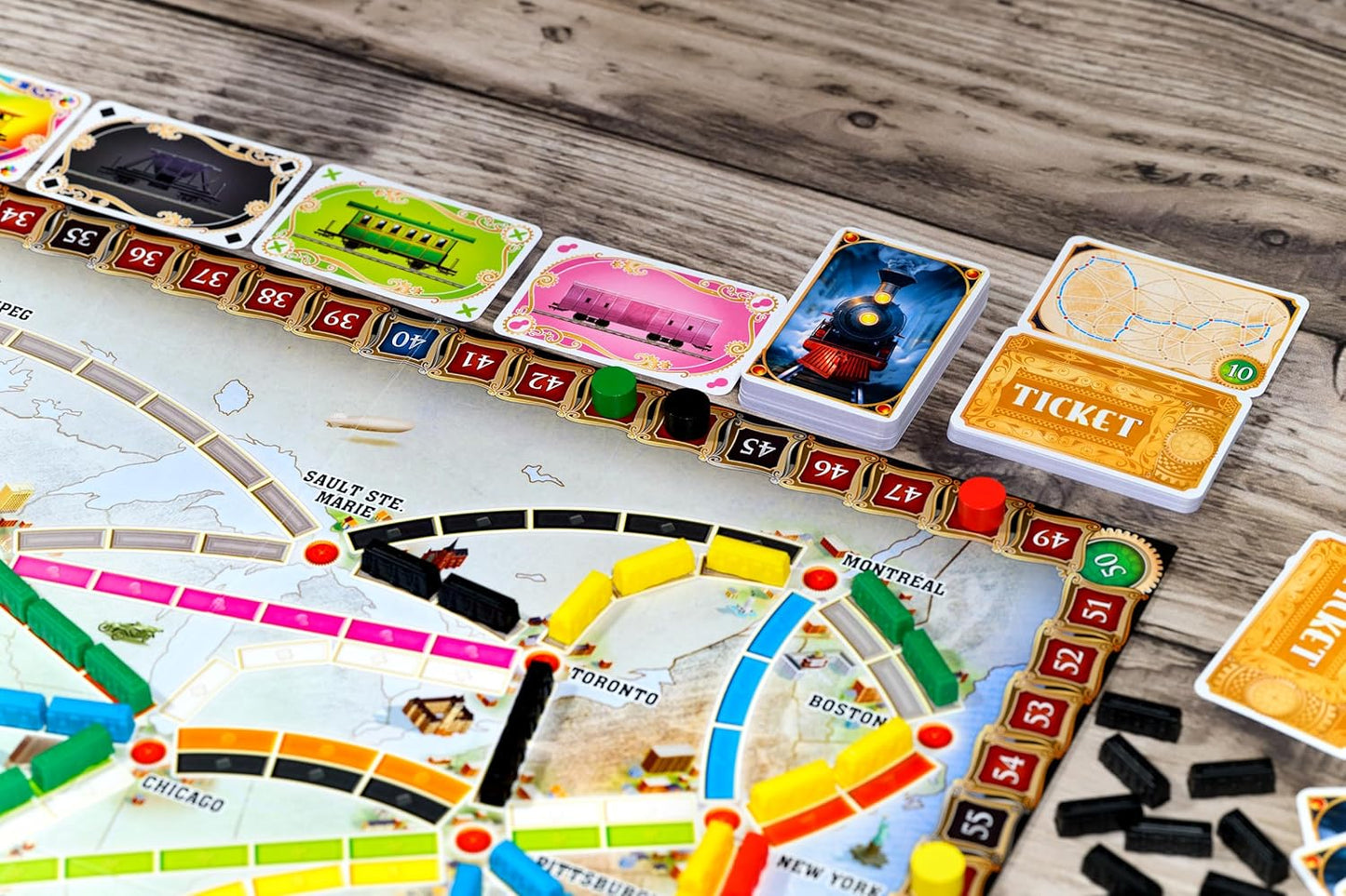 Close-up of the Ticket to Ride board game, showing train pieces, game cards, and the score track