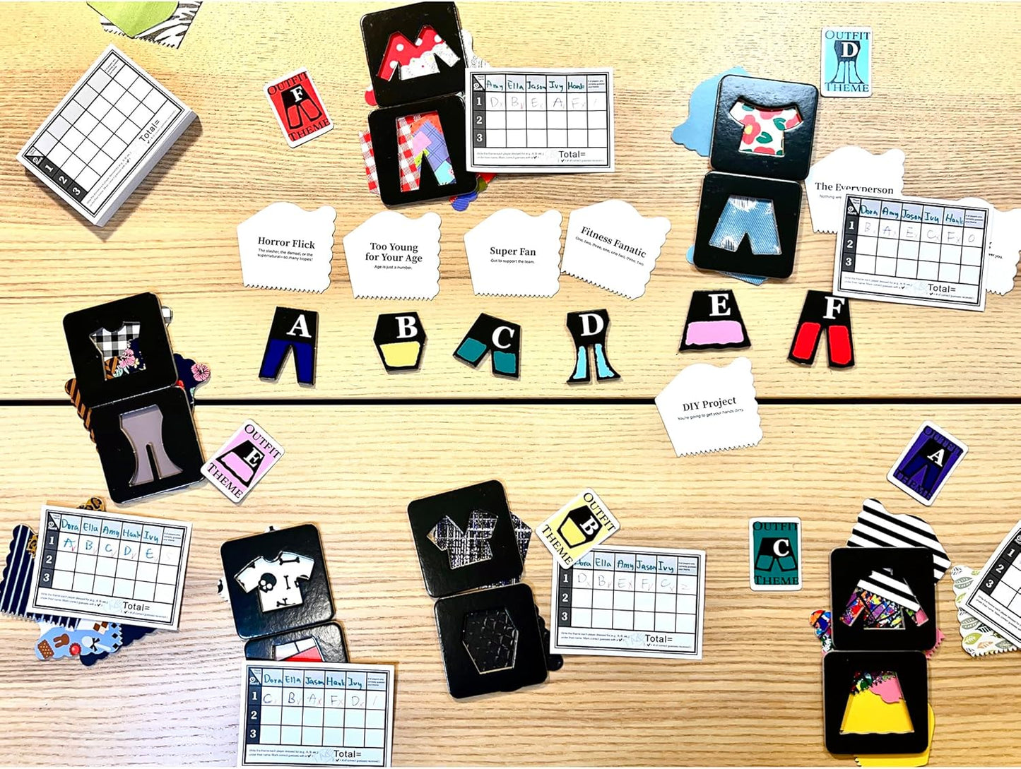 Colorful clothing game pieces, theme cards, and scorecards from a fashion board game spread on a wooden table
