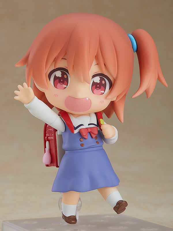 Nendoroid of a girl with pink hair and red eyes wearing a blue dress with a backpack waving on color background