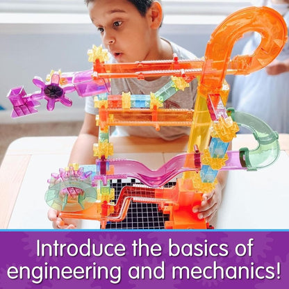 Young boy plays intently with a colourful, translucent marble run and gear STEM toy