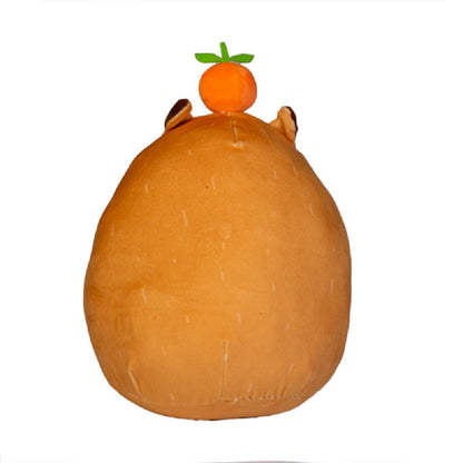 The adorable Smooshos Pal Capybara plush, a chubby brown toy with tiny ears, is topped with a vibrant plush orange fruit against a white background