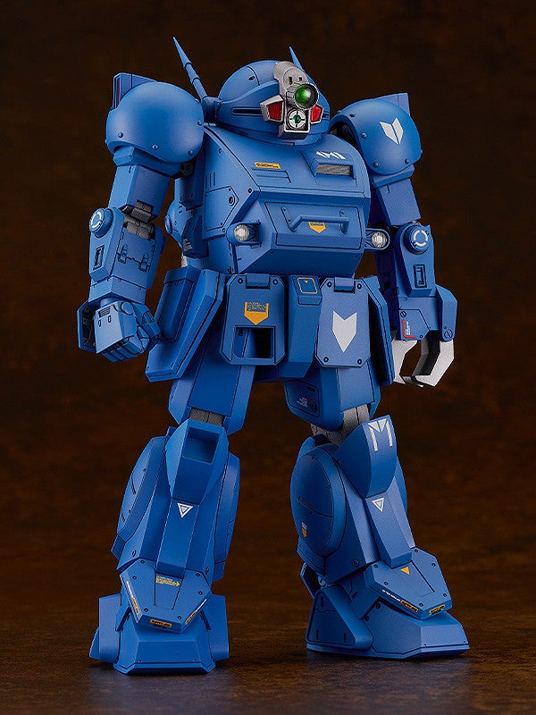 A dark blue, armored robot figure stands, featuring a round head with a green eye and various warning symbols