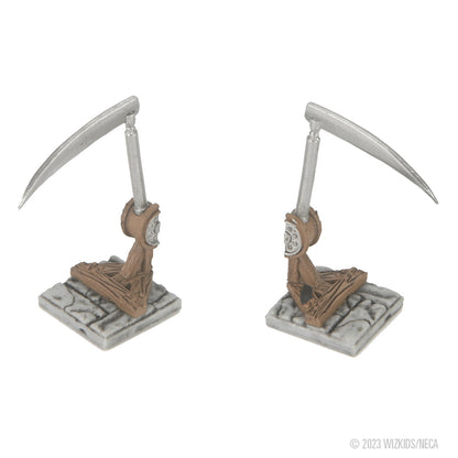 Two identical miniature scythe traps, with silver blades, brown mechanisms, and grey stone bases