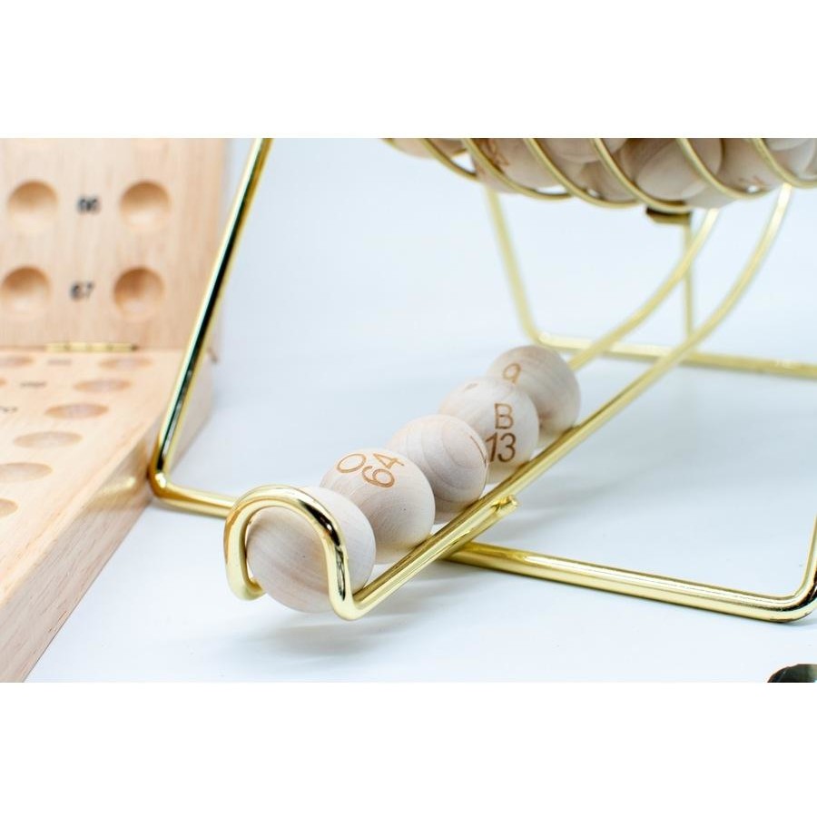 A close-up of a Bingo set shows light wood balls with numbers like 06, 49, and B13 on a golden metal track, with a wooden calling board in the background