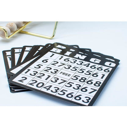 A fanned stack of black and white bingo cards with a gold wire cage holding wooden balls in the background