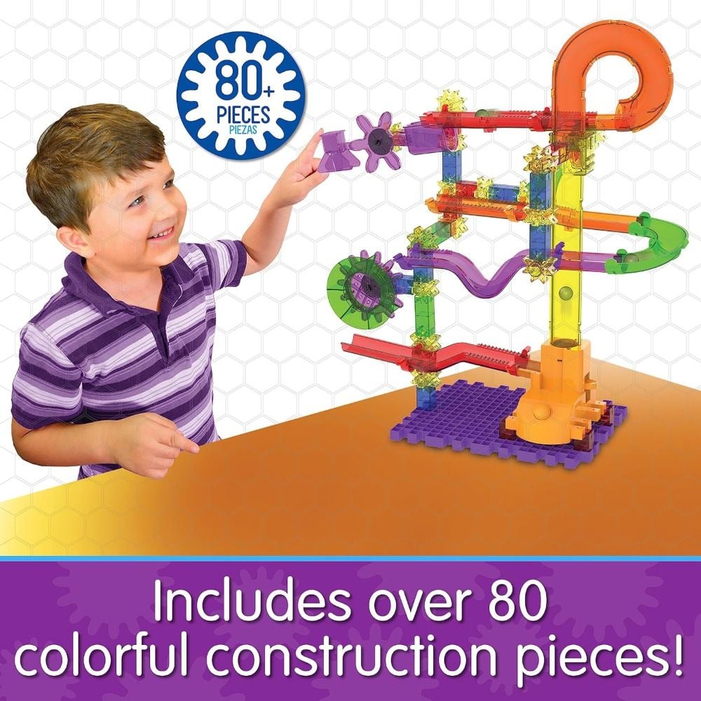 Smiling boy plays with a colourful, translucent 80+ piece marble run construction toy featuring winding tracks and gears