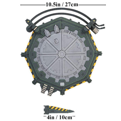 A dark green hexagonal sci-fi terrain piece with a segmented grey circular center, yellow hazard stripes on the edges, and a smaller matching wedge piece
