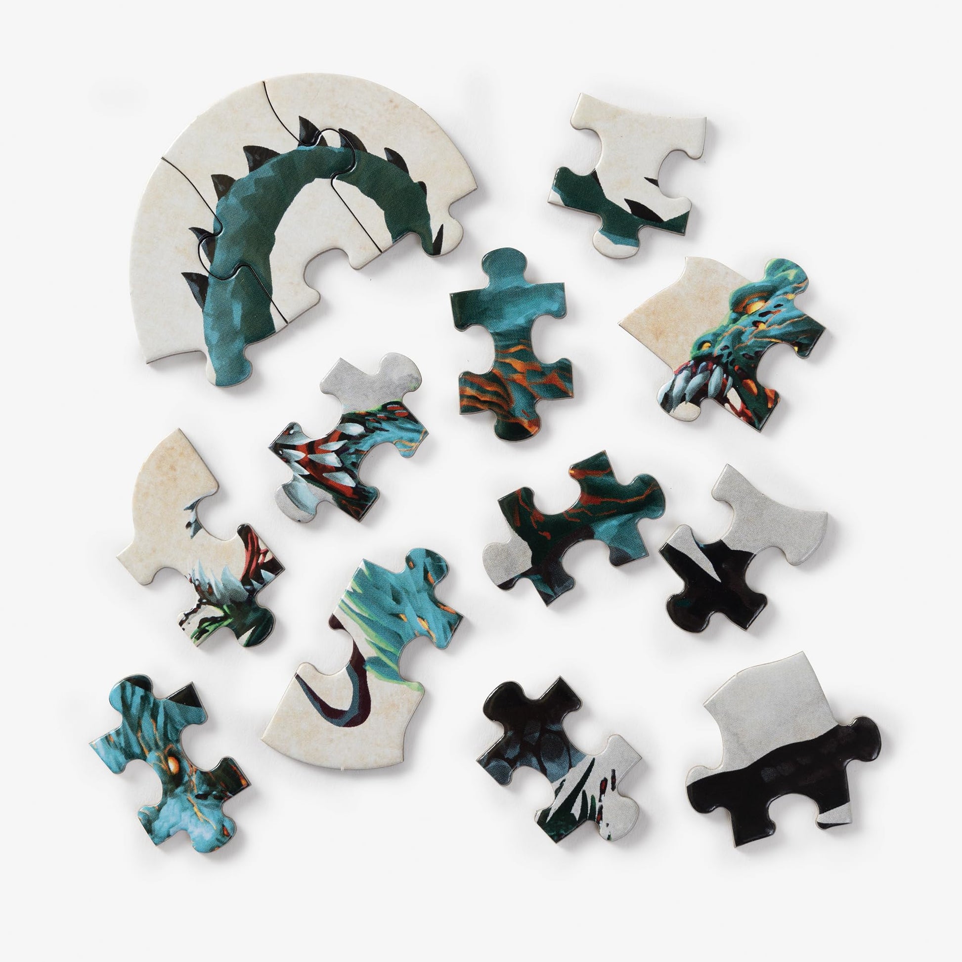 Various pieces of a Clarkson Potter Dungeons & Dragons Mini Shaped Demogorgon Edition jigsaw puzzle, partially assembled and scattered, depicting a green and blue monster with orange accents