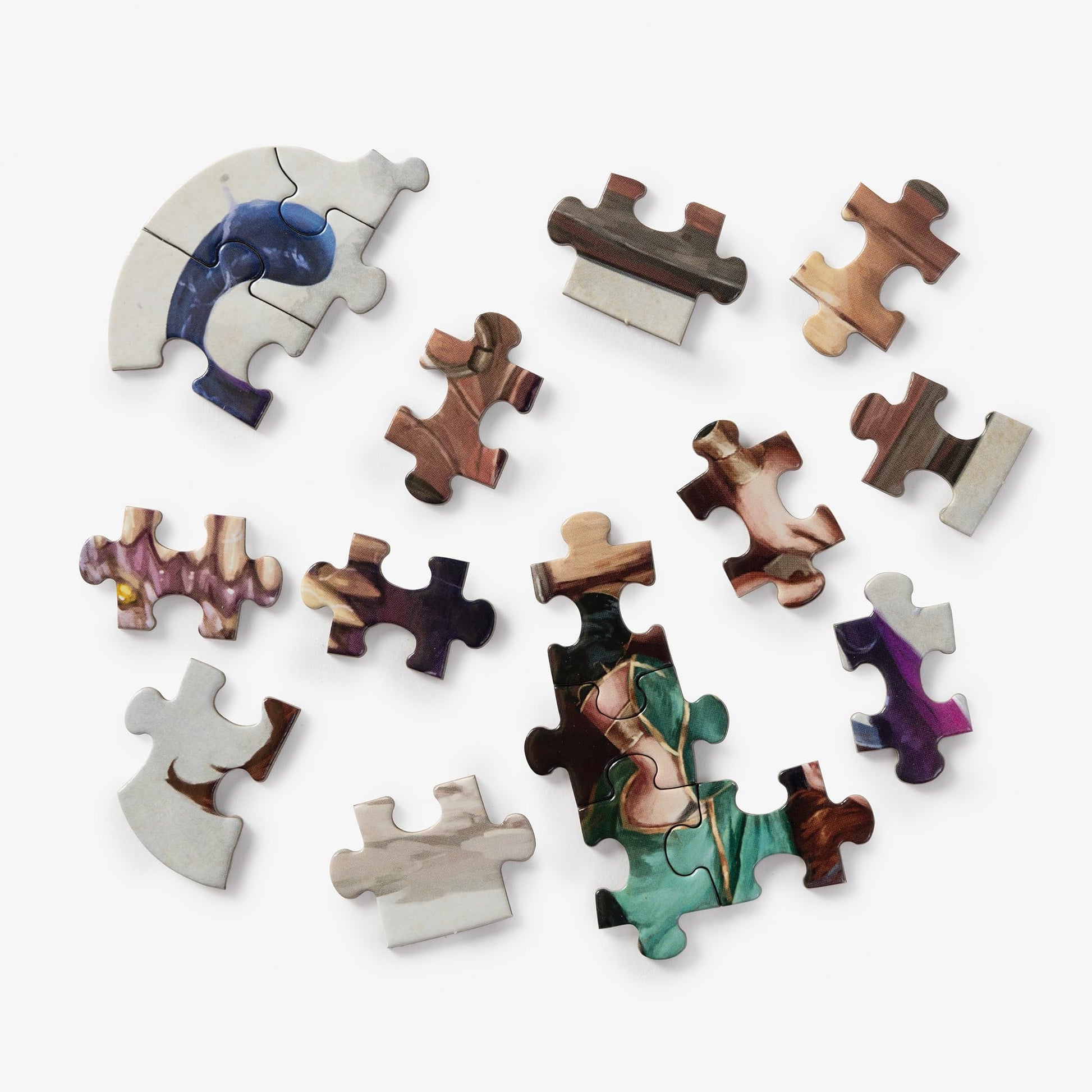 Numerous colorful pieces of a Dungeons & Dragons Mini Shaped Mimic Edition jigsaw puzzle are scattered across a white surface, with a few segments connected