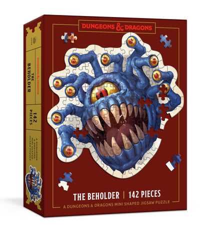 D&D The Beholder 142-piece shaped jigsaw puzzle box. Features a blue, multi-eyed monster with sharp teeth on a red background with gold accents